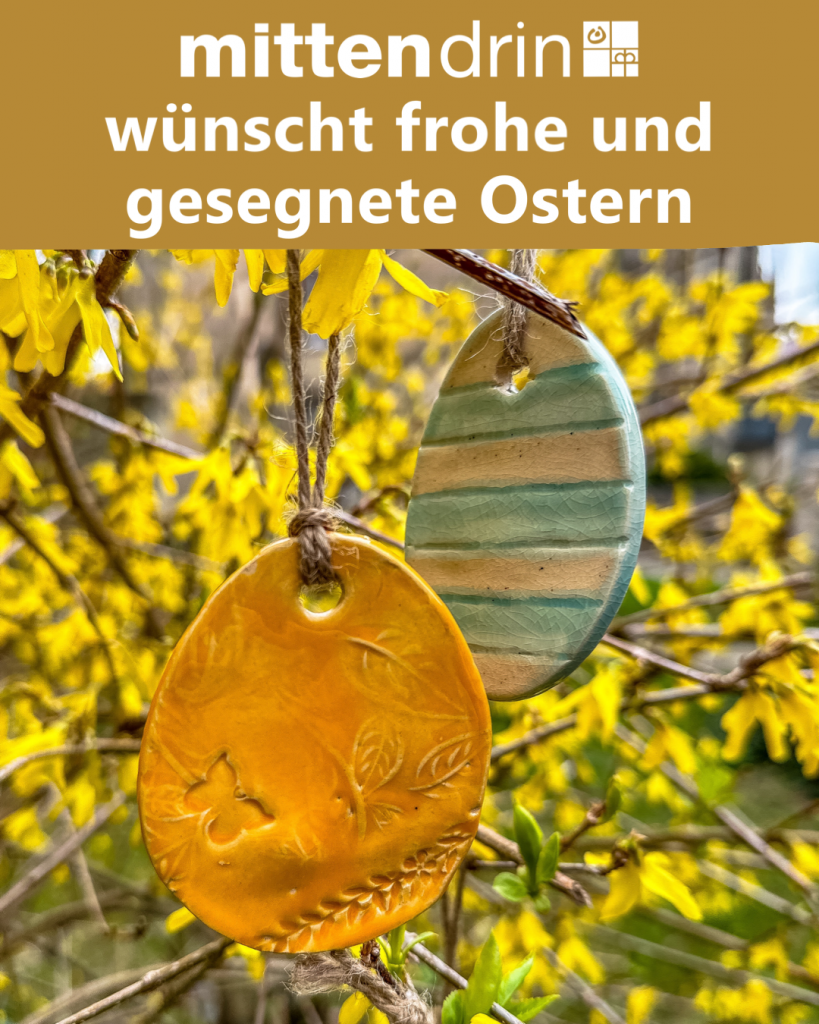 Ostereier-Anhänger aus Ton hängen an einem gelben Strauch