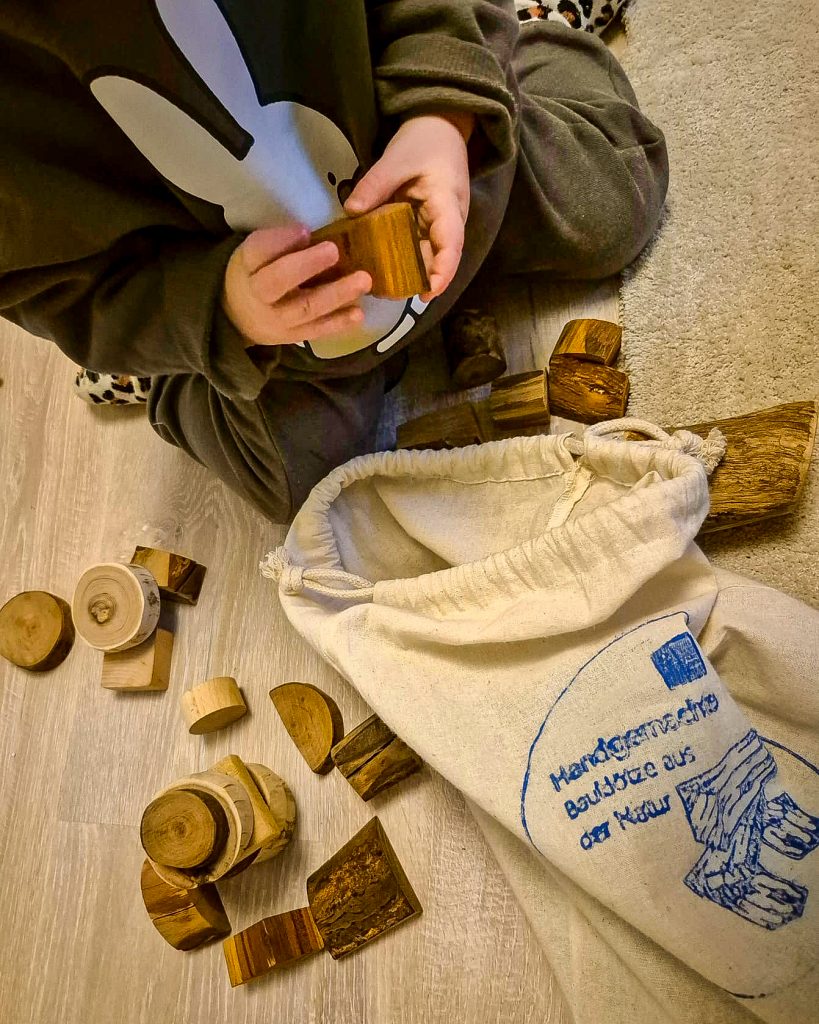 ein Kind spielt mit den Bauklötzen aus der Natur von den Diakonie Werkstätten Halberstadt